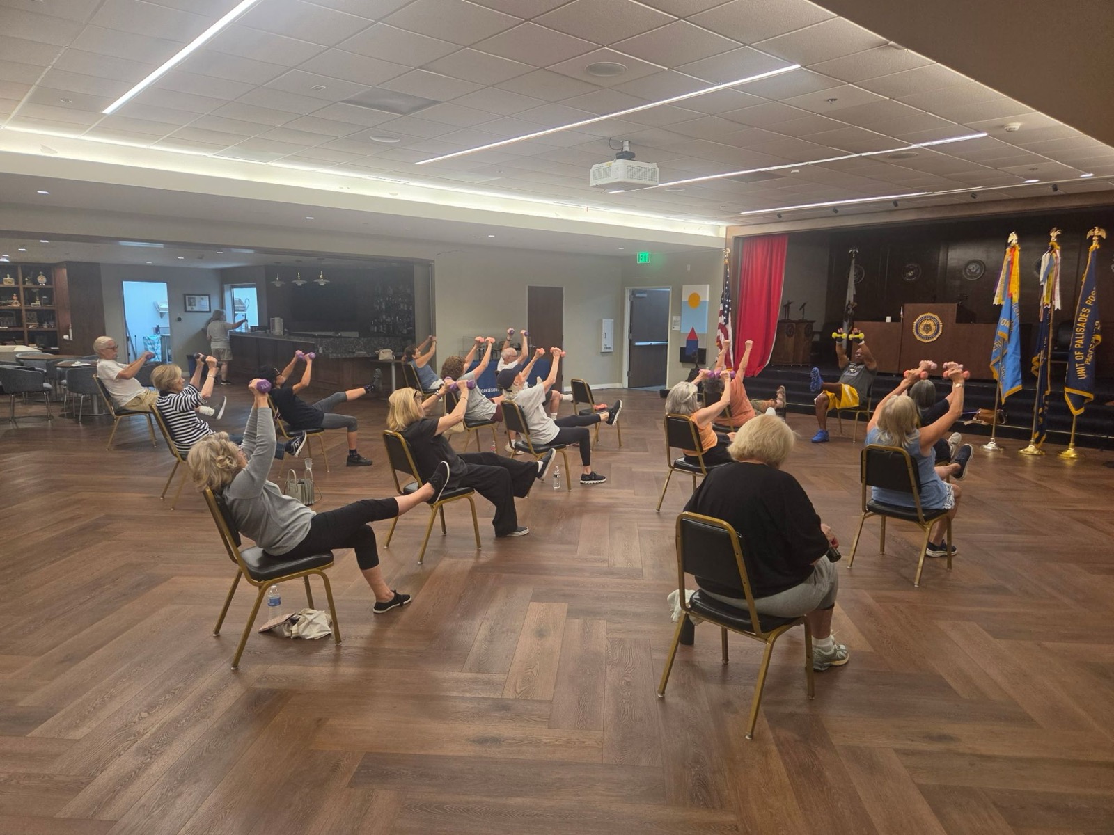 Senior fitness class doing seated overhead presses with leg raises