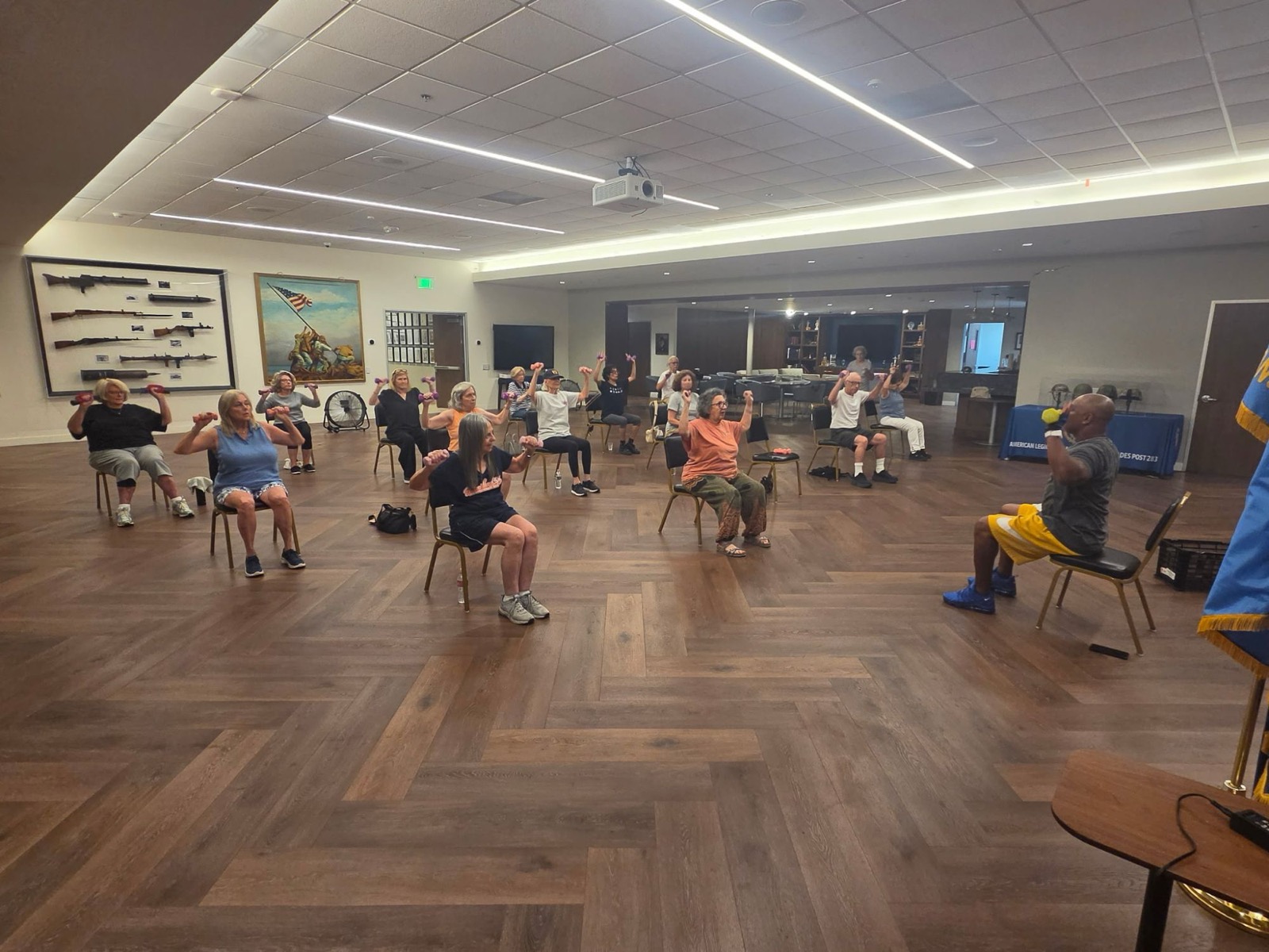 Coach Todd leading a seated strength class for older adults with light dumbbells